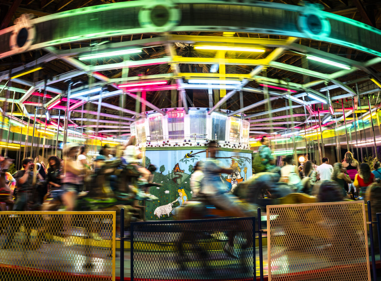 Colorful, spinning carousel with blurred riders and bright neon lights