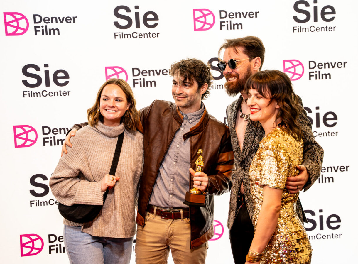 Four people smiling at Denver Film event, posing with a trophy