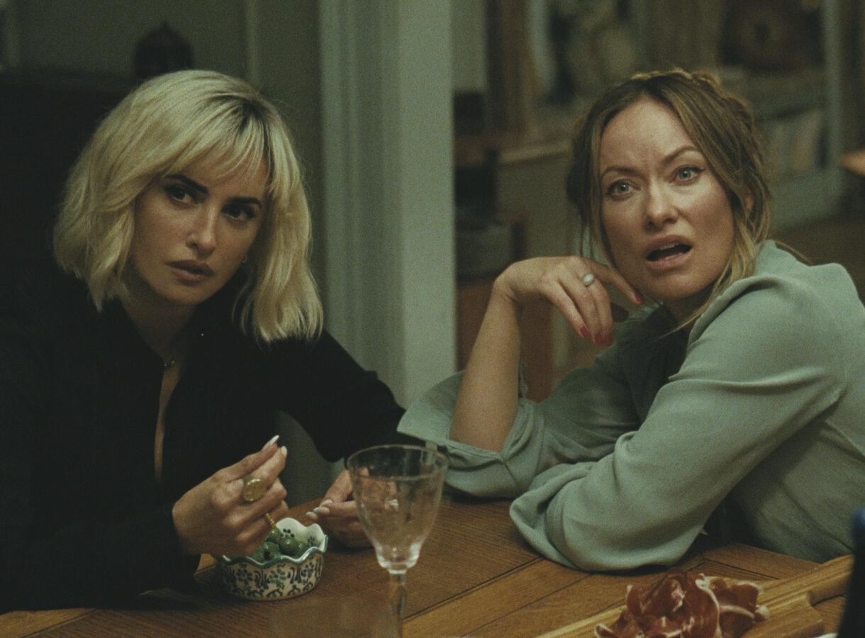 Two women sitting at a dining table, displaying curious expressions