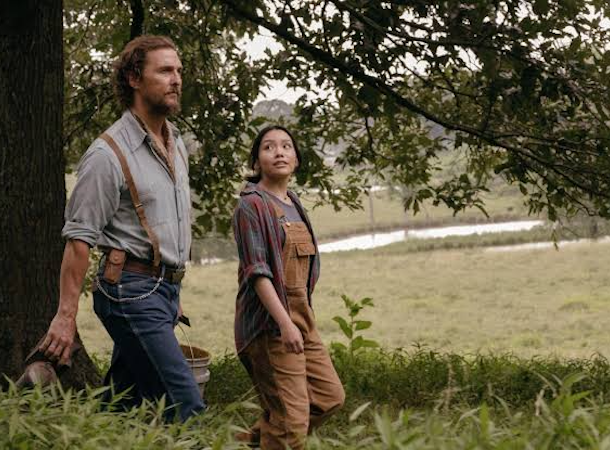 Amziah and companion walking through a grassy field, surrounded by trees, with engaged expressions