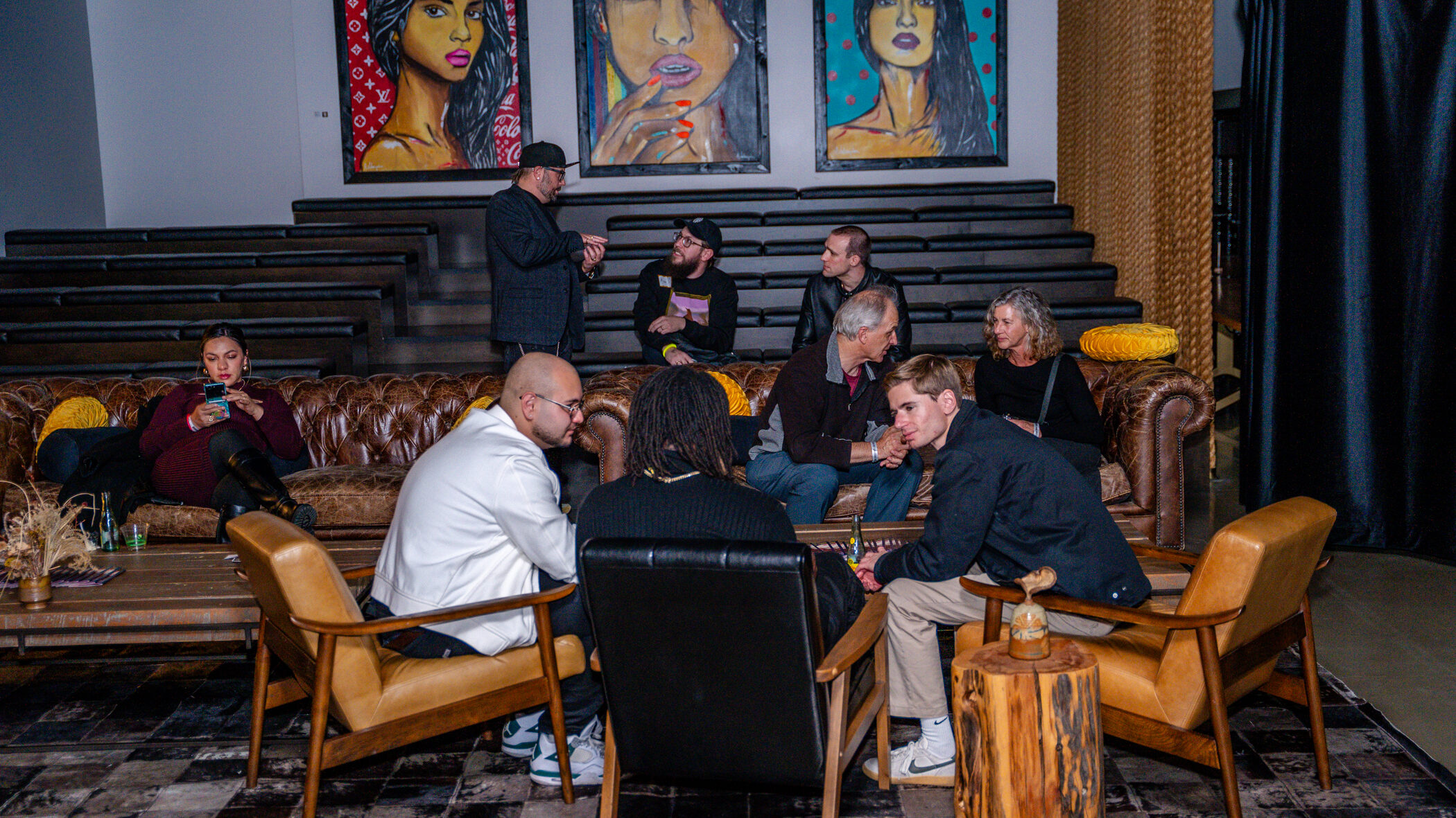 [gpt-4o]: People gathered in a lounge with vibrant portraits on the wall